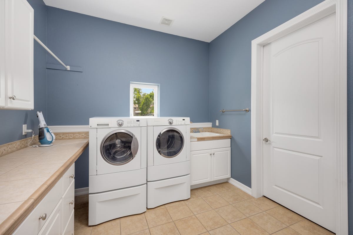 Modern laundry room with side-by-side washing machines and storage cabinets in Brownsburg