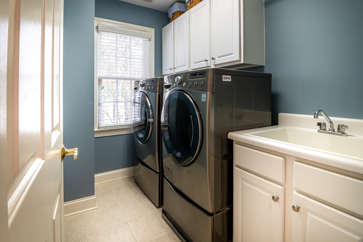 Modern laundry room with front-load washing machine and white cabinets in Brownsburg